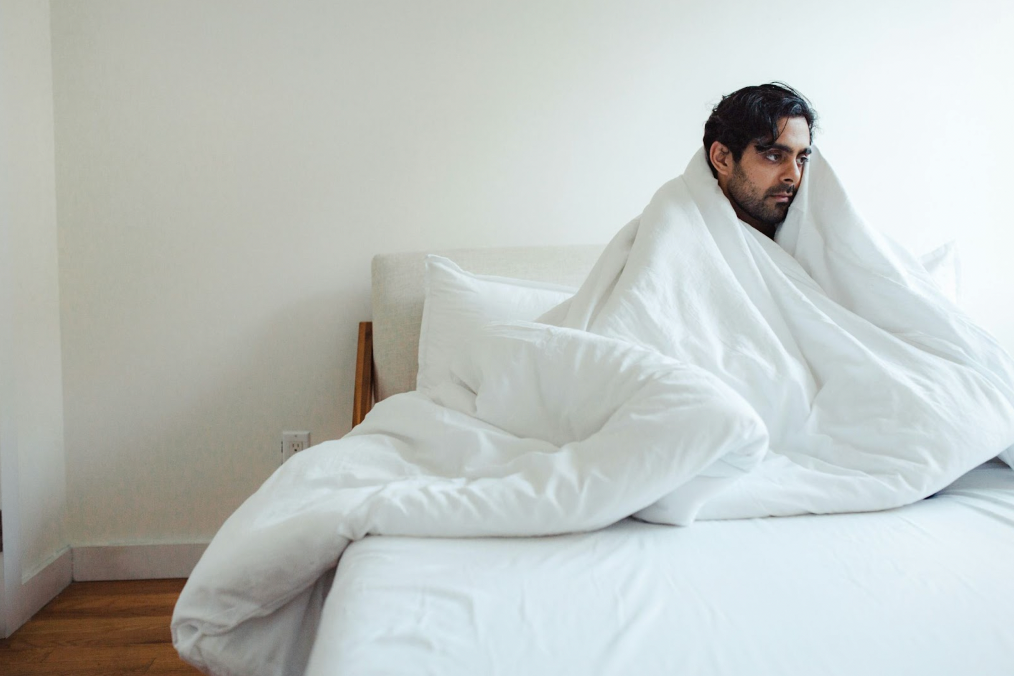 anxious man in bed sheets